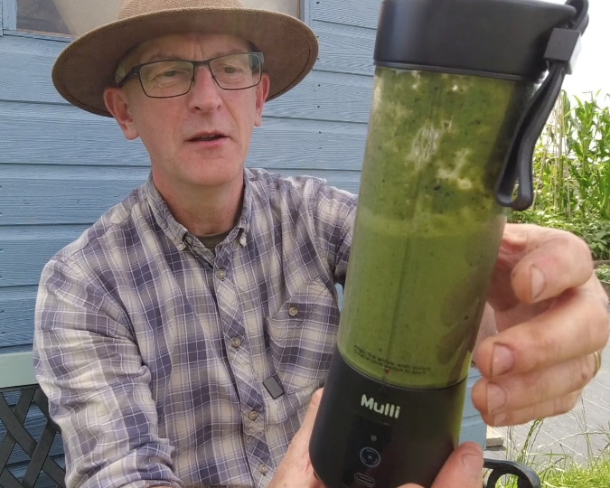 Man holding a blender in his garden